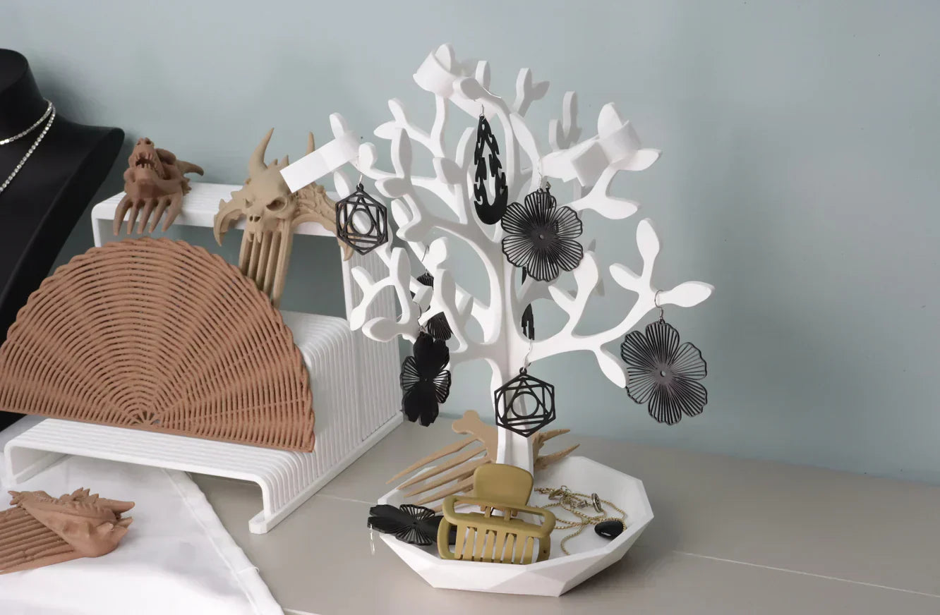 3D-gedruckter weißer Schmuckbaum-Organizer mit Ohrringen, Haarklammern und Accessoires auf einem Schminktisch.